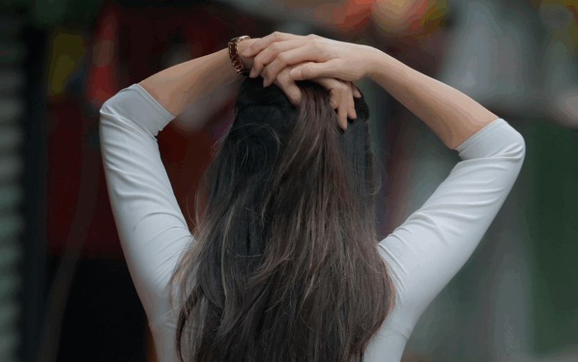 髪の毛の画像。若い女性が頭脳上に手を置いている後ろ姿。