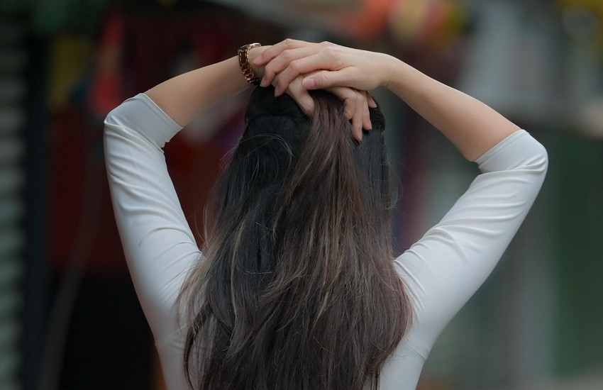 髪の毛の画像。若い女性が頭脳上に手を置いている後ろ姿。